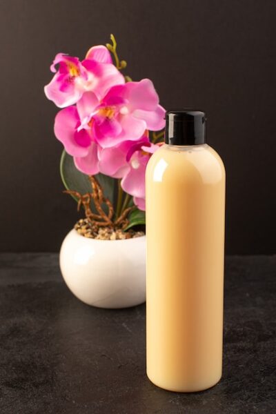 front view cream colored bottle plastic shampoo can with black cap with flower isolated dark background cosmetics beauty hair 140725 18107